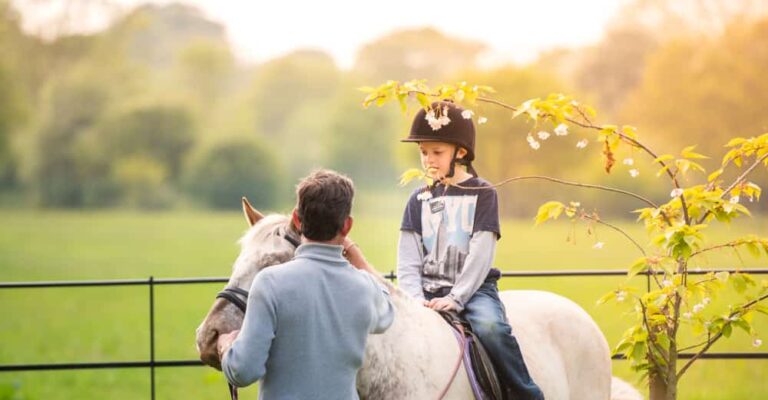 Horse-riding instructor teaching a beginner rider in an arena