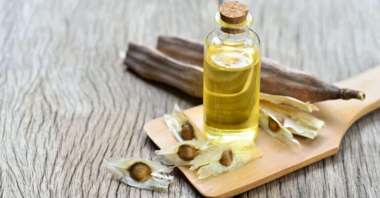 Bottle of essential oil beside dried botanicals on a wooden table