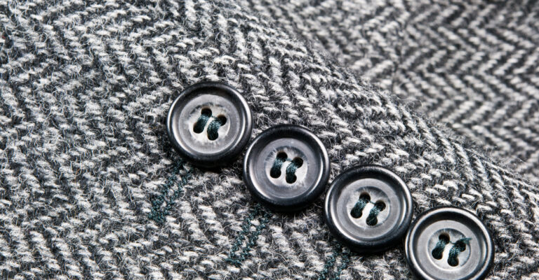 Close-up of black buttons on gray herringbone tweed fabric
